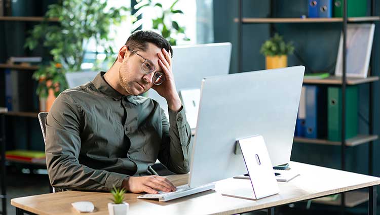 Frustrated young fundraiser at desk, overwhelmed by complex planned giving tasks without proper training or mentorship.