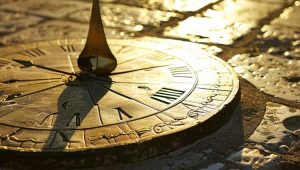 Bronze sundial casting a long shadow on stone, symbolizing timelessness and enduring values in fundraising.