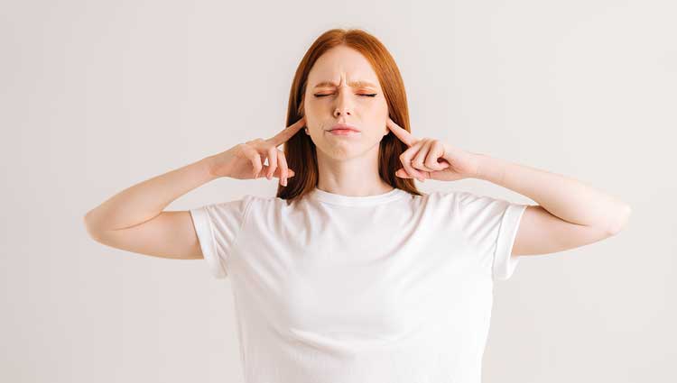 Woman in white short blocking / covering her ears.