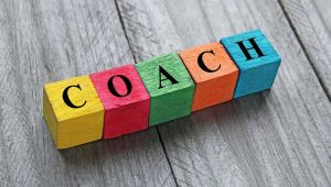 Philanthropy coach concept represented by colorful blocks spelling 'COACH' on a wooden background.