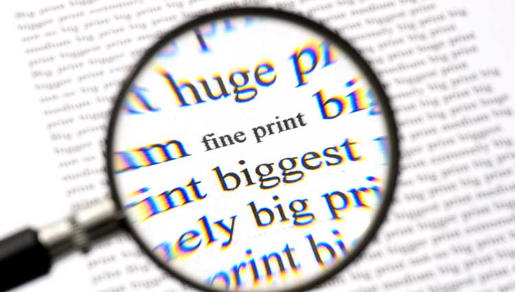 An image of the words "fine print" getting larger in a magnifying glass, to symbolize reading the fine print about a new RMD age.