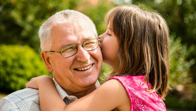 granddaughter whispers into grandfather's ear