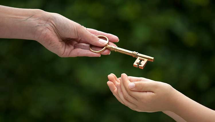 An image of an adult's hands passing a key to a child's hands, symbolizing the passing down of assets for future generations, to illustrate a blog on the importance of having an estate plan.