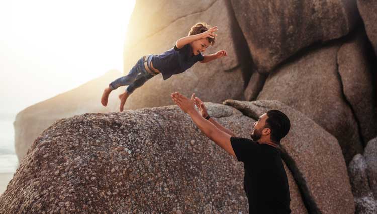 Son trusts father as he dives into his arms from above height.