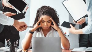Overwhelmed nonprofit professional surrounded by distractions, symbolizing toxic busyness and poor time management