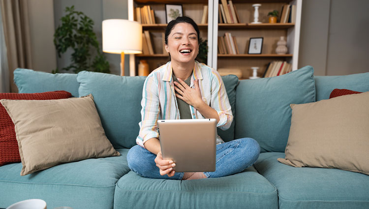 An image of a woman laughing at donor thank-you videos on computer.